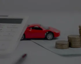 pénzérmék felsorakoztatva számológép és autó mellett